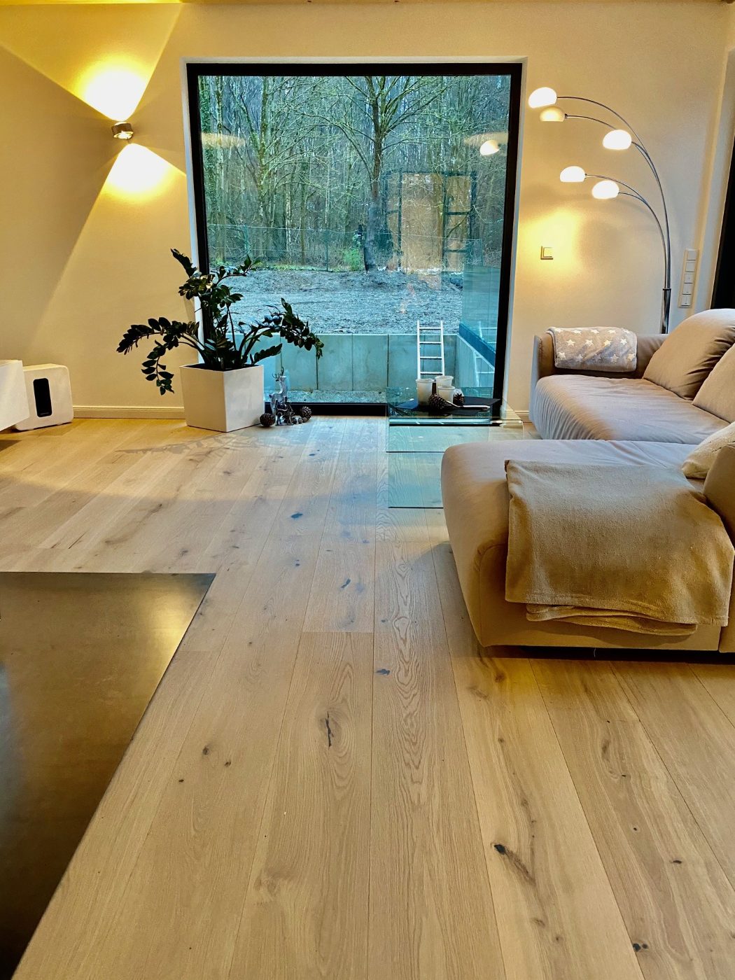 Wohnbereich mit großer Fensterfront zum Wald und hellen Eichen-Landhausdielen in Rohholzoptik
