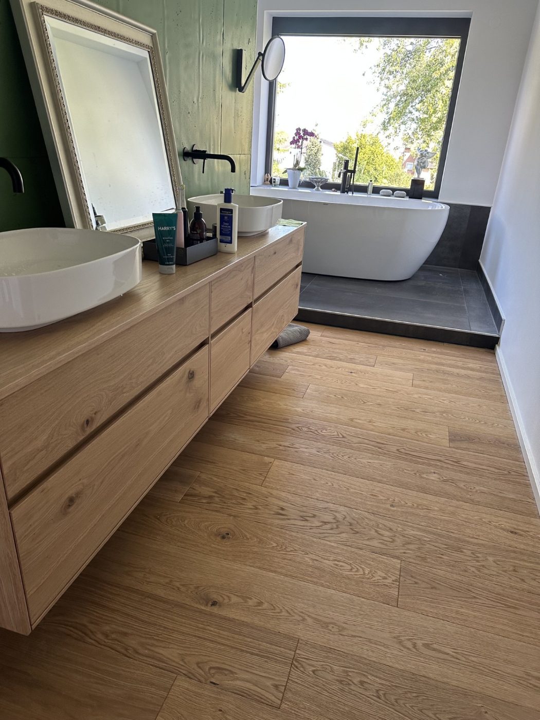 Badezimmer mit Holzwaschtisch, grüner Wand und Eichen-Landhausdielen